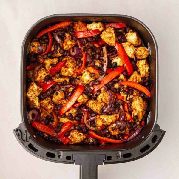 Red peppers, beans, onion and chicken chunks in an air fryer for Air Fryer Mexican Chicken.