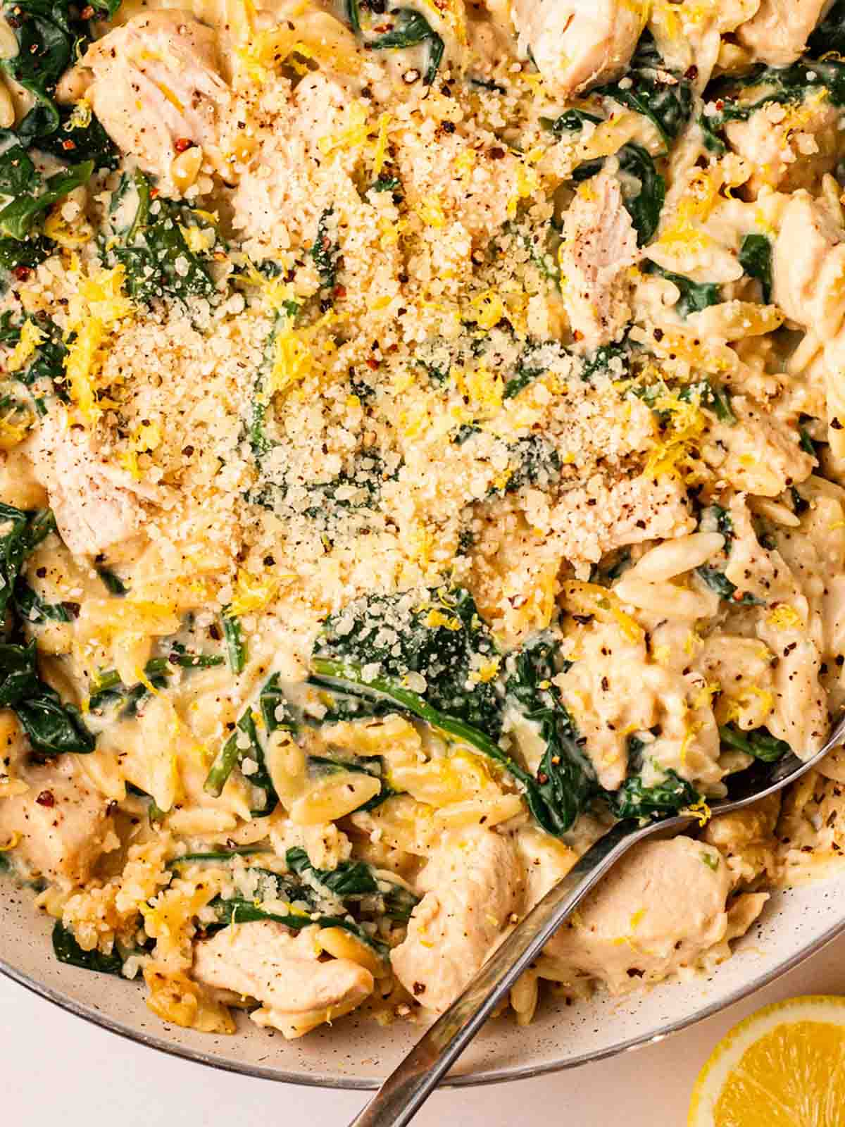 A close look at a big pot of orzo with chicken, lemon, parmesan and spinach.